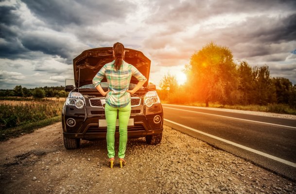 autopom extended car warranty woman in front of car by the side of the road open hood beautiful sunset in the background